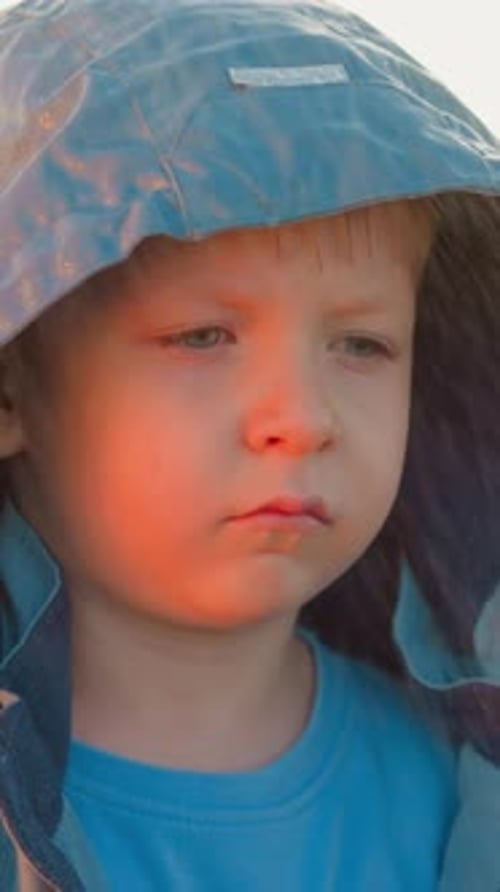 Pensive Boy in Hooded Jacket During Golden Hour