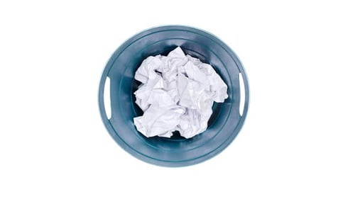 Plastic trash can being filled with crumpled sheets of white paper, isolated on a white background