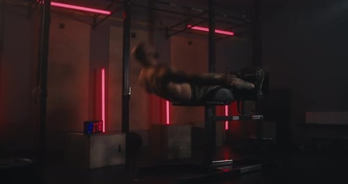 Active Male Athlete is Engaged in Intense Training and Pumps Up His Abs in a Modern Gym with Red