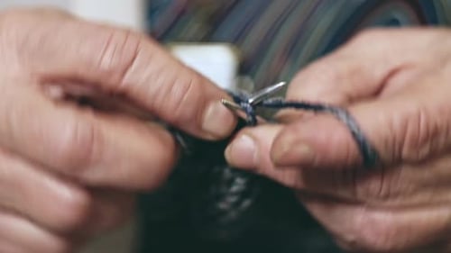 Closeup View with Rack Focus of Hands of Elderly Woman Knitting with Needles