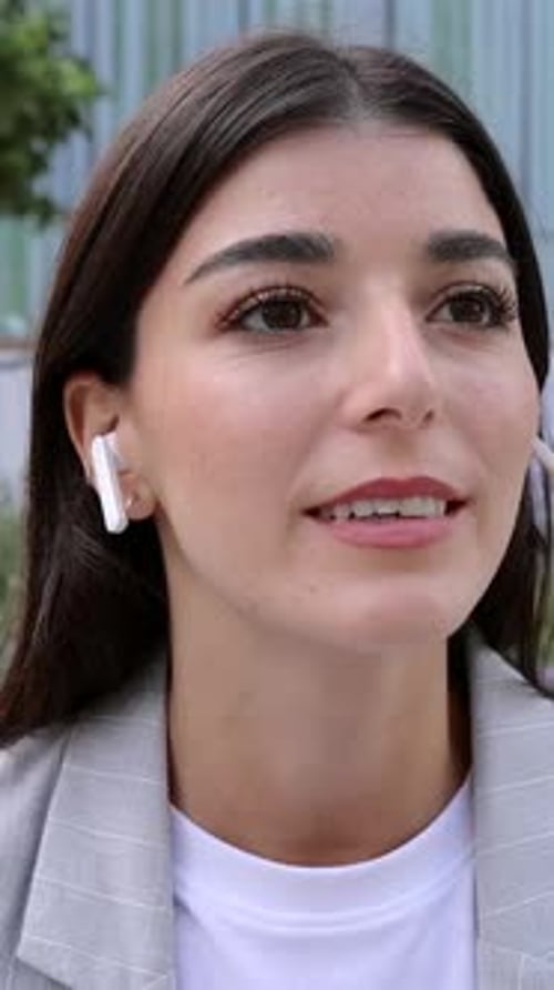 Smiling Woman Talking with Wireless Earbuds, Close Up