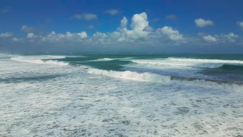 Aerial View of Seminyak Bali's Vibrant Coastline with Powerful Waves Crashing Against the Shore