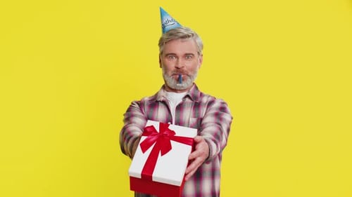 Mature Man Handing Presenting Birthday Gift Box Cone Hat Blower Joyful Expression Festive Atmosphere