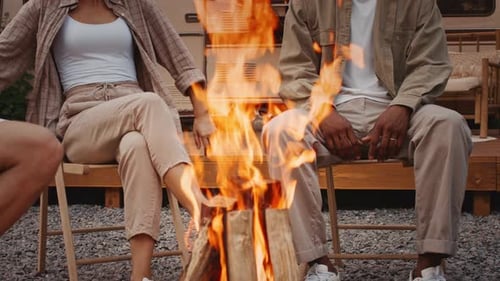 Friends Relaxing by a Campfire Near a Camper