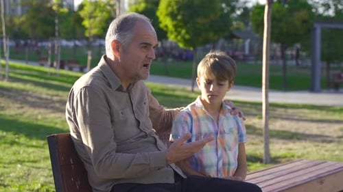 Grandfather Comforts Grandson in Sunny Green Park