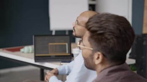 Verschiedene männliche Programmierer diskutieren während der Office-Präsentation über Code auf dem Bildschirm