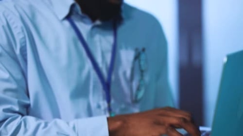 Man Types on Laptop in Data Center