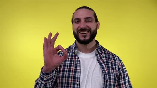 Man Gives OK Hand Sign on Yellow Background