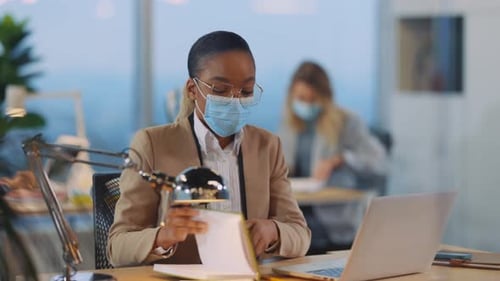 Woman with face mask working at desk in office