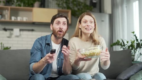Exited couple sport fans watch football together and celebrating win goal score of match game