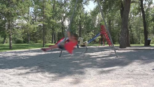 Children Swinging On Swings In Park