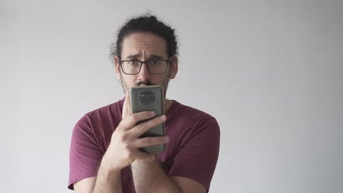 Man Looks Anxiously at Phone Camera Indoors