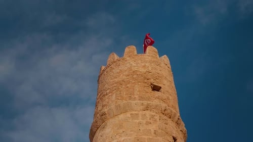 Historic Stone Tower with Flag Against Blue Sky