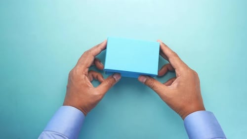 Vue du dessus de la personne ouvrant une petite boîte-cadeau vide