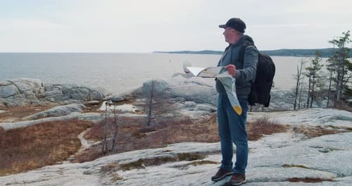Man Exploring Rocky Coastline Reading a Paper Map