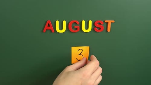 Hand sticking a sticker 3 August calendar day on school board. 3 date of august. Third day