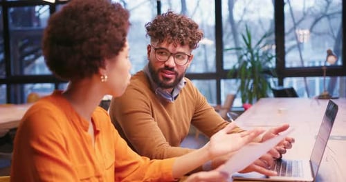 Smiling Happy Colleagues Analyzing Documents Using Laptop Working in Modern Office Sitting on Table