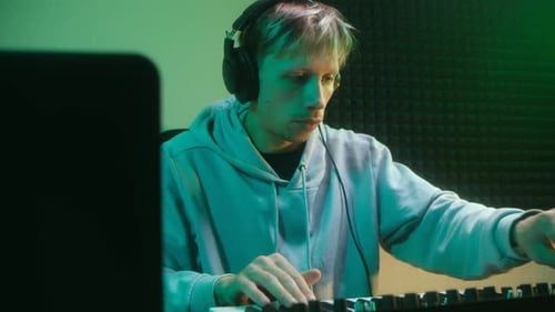 Man Plays Keyboard in Music Studio with Headphones