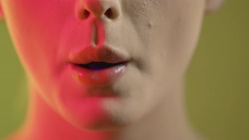 Primer plano de la boca de una mujer masticando y sacando una lengua de color azul, foto de estudio