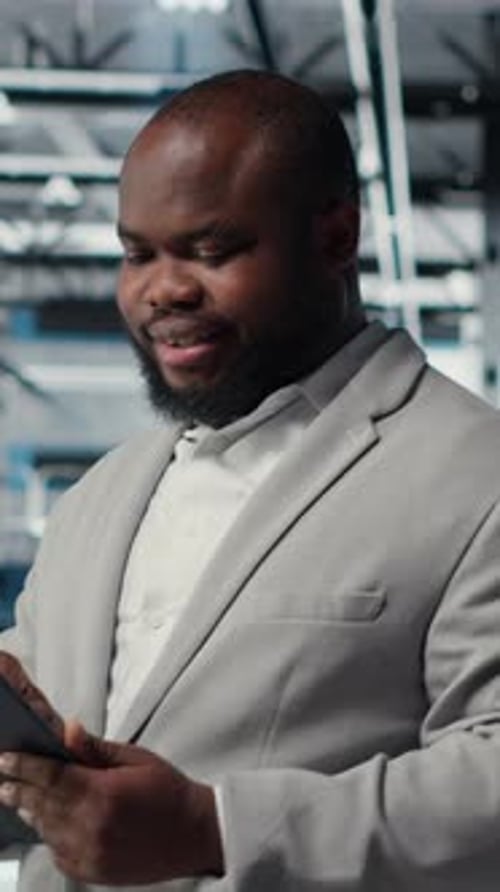 Vertical Video Engineer Working in Server Farm Using Tablet to Analyze Data