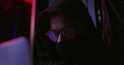 Hooded Person Working on Computer in Server Room