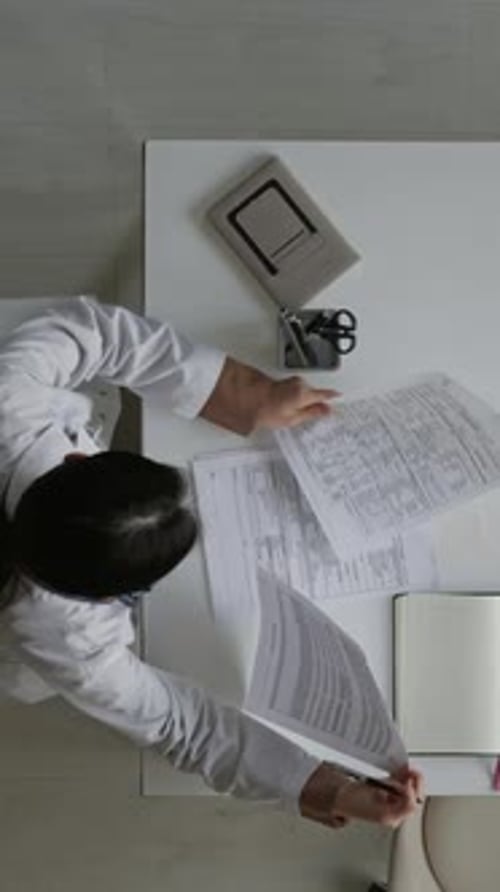 Vertical of Female Doctor Working with Clinical Records in Hospital Office