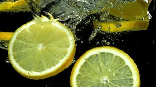 Lemon Slices Falling into Water on Black Background