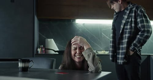 A Girl is Crying and Leaning on the Table While Her Boyfriend Stands Aside During a Quarrel in the
