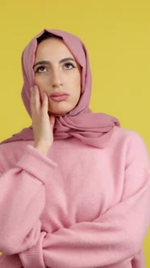 Thoughtful Woman in Headscarf Posing Against Yellow Backdrop
