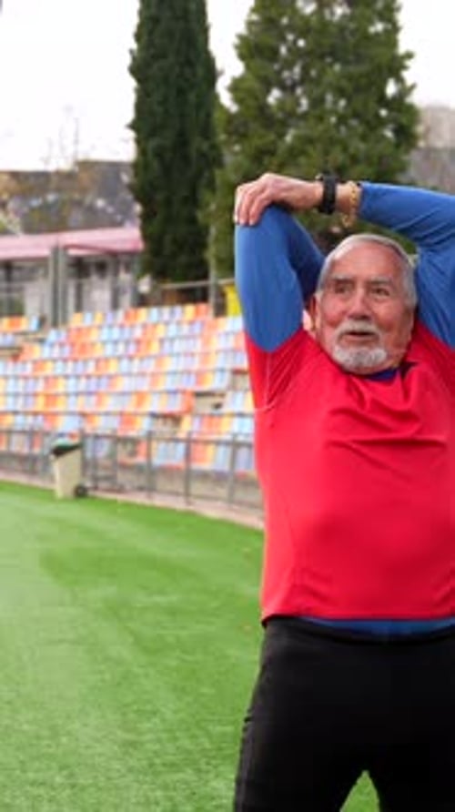 Senior Man Stretching Arms Outdoors on Sports Field