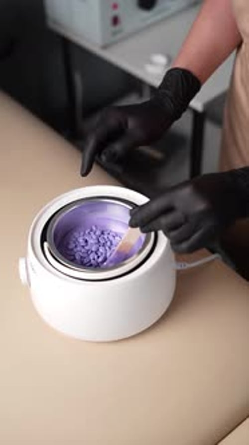 Master mixes the heating wax with a wooden spatula before the depilation procedure. Depilation with