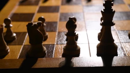 Schachfiguren auf einem Schachbrett. Die Kamera bewegt sich von links nach rechts. Die Stücke werden beleuchtet