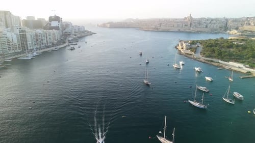 Boats cruise below drone at sunrise in Malta