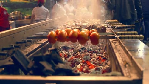 Grilling Tomato and Meat on Skewers. Outdoor Grill Restaurant. Automatically Rotating Skewers