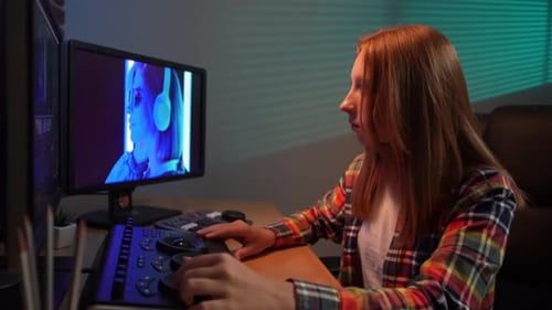 Young Adult Editing Video at Desk in Dark Room