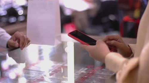 An upwardly mobile Asian Muslim woman using a mobile phone to pay for a product at a sale terminal w