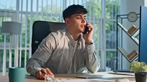 Young Man Talking on Phone at Office Desk