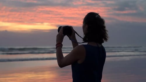 Femme prenant des photos d'un magnifique coucher de soleil avec un appareil photo sur la plage, Super Ralenti 240 images par seconde