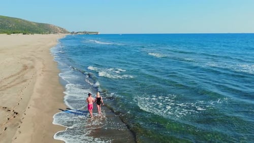 Young beautiful couple walking together on sandy beach along sea,
