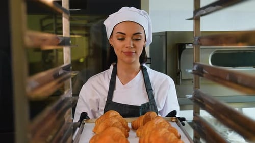 Female Baker Holding Tray of Fresh Croissants
