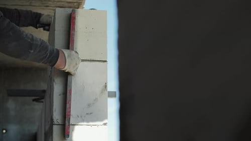Worker Checking Vertical Alignment of Aerated Concrete Blocks