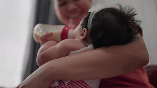 De cerca La joven madre amamanta a su bebé con leche materna de un biberón. El niño come y mira