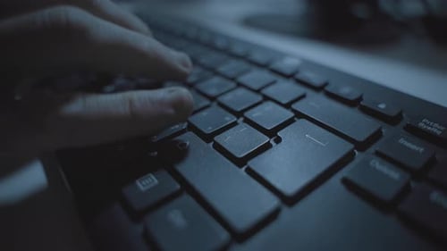 Tapez à la main dans un bureau sombre sur le clavier de l'ordinateur en appuyant sur le clavier de retour ou sur le clavier d'entrée. Hacker