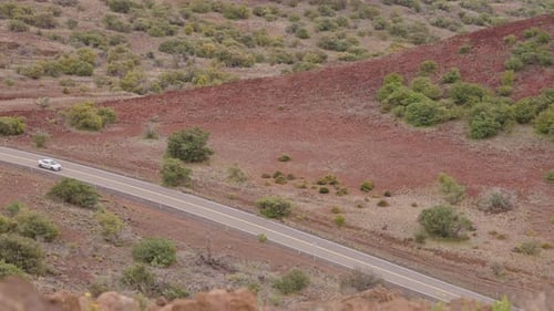 Slow Motion Car On Road With Red Dirt Vegetation In Valley From Mauna Kea Lookout, Hawaii 4K