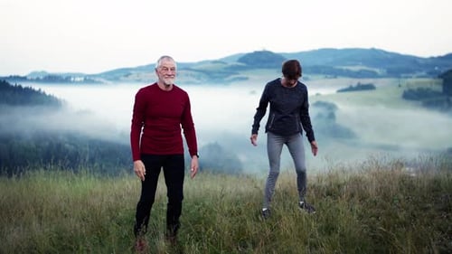 Senior couple stretching outdoors in misty mountain landscape