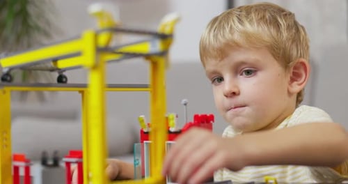Child Boy Playing and Building with Colorful Plastic Bricks at the Table