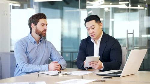 Business men discussing financial market data using laptop and digital tablet. Two diverse employees