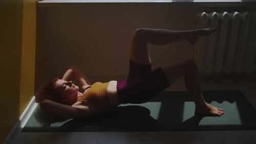 Woman Does Leg Lifts on Yoga Mat at Home