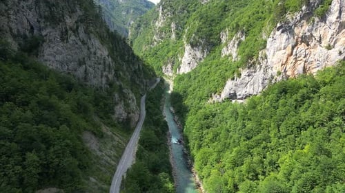 Ein sauberer Gebirgsfluss fließt durch eine riesige Schlucht, an seinen Seiten erstrecken sich grüne Berge.