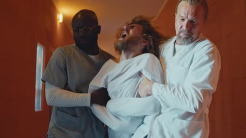 Struggling Patient Escorted By Two Professionals
